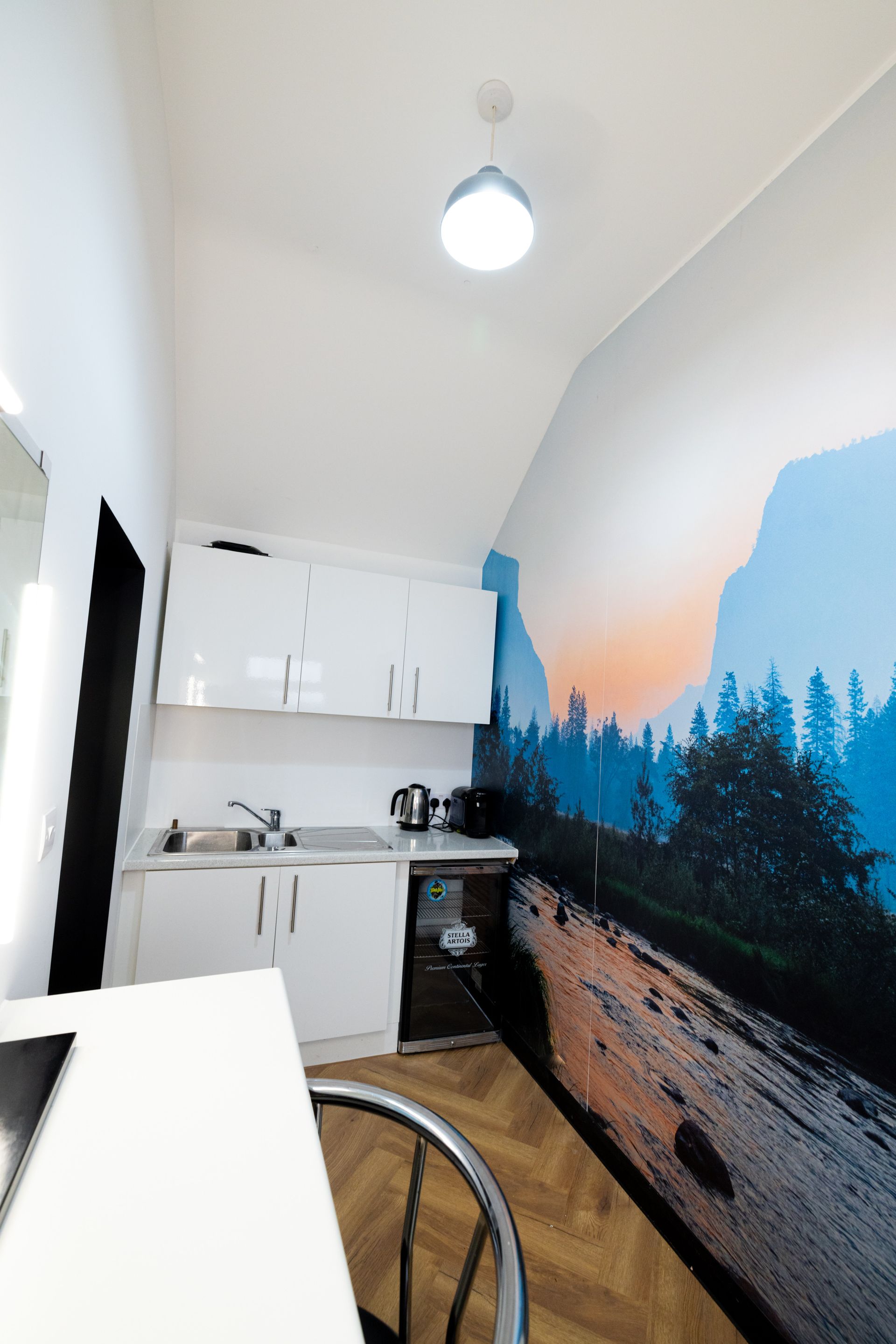 A kitchen with a picture of a mountain on the wall.