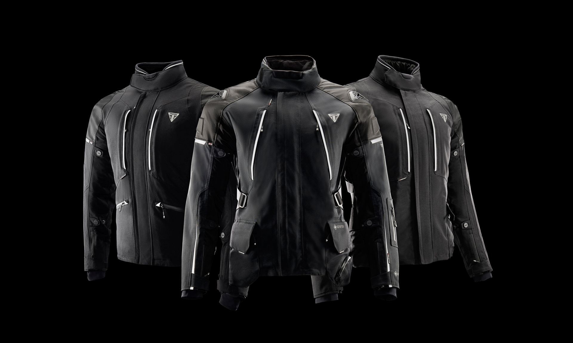 three black jackets are sitting next to each other on a black background .
