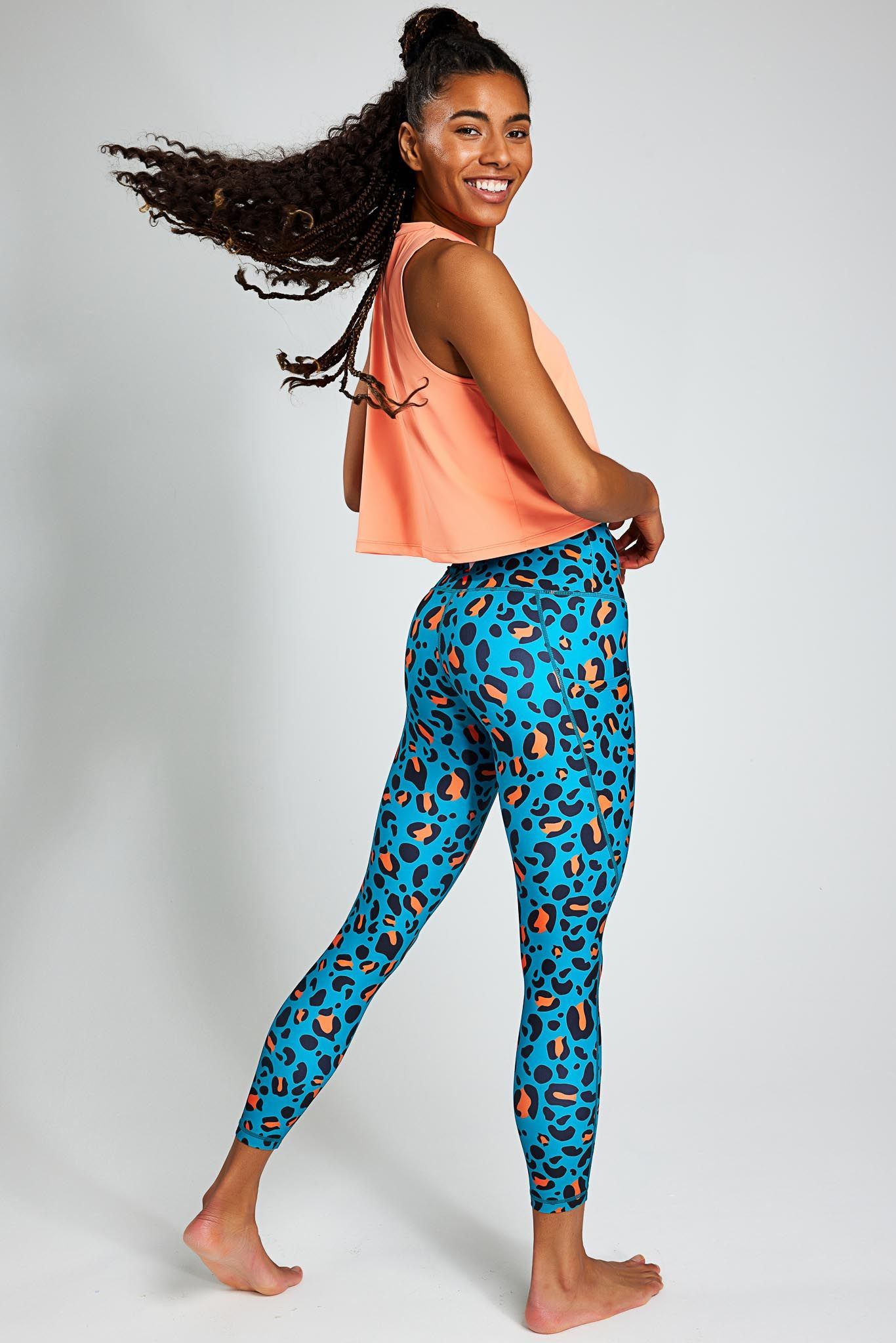 a woman is wearing a crop top and leopard print leggings .