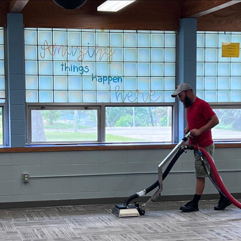 A man is using a vacuum cleaner in front of a sign that says things happen here