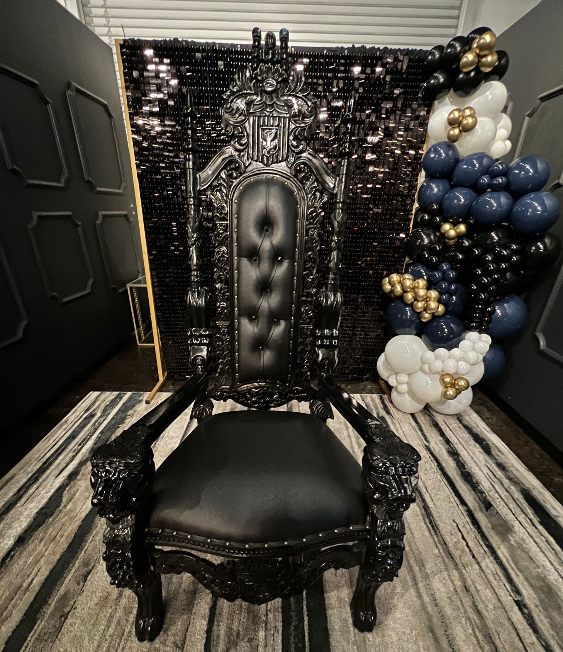 A black chair is sitting in front of a wall of balloons.