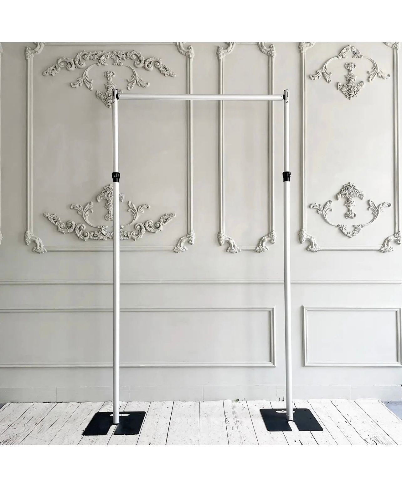 A white clothes rack is sitting in front of a white wall.
