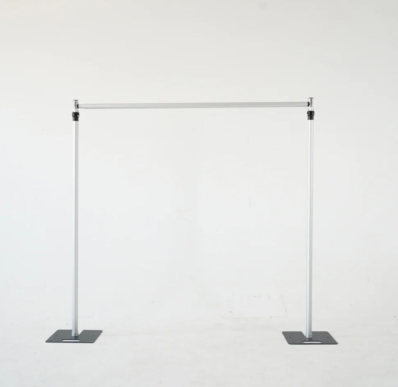 A white pole with two black bases is sitting on a white surface.