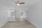 An empty room with a ceiling fan and a mirror.