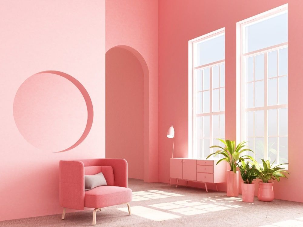 A living room with pink walls and a pink chair.