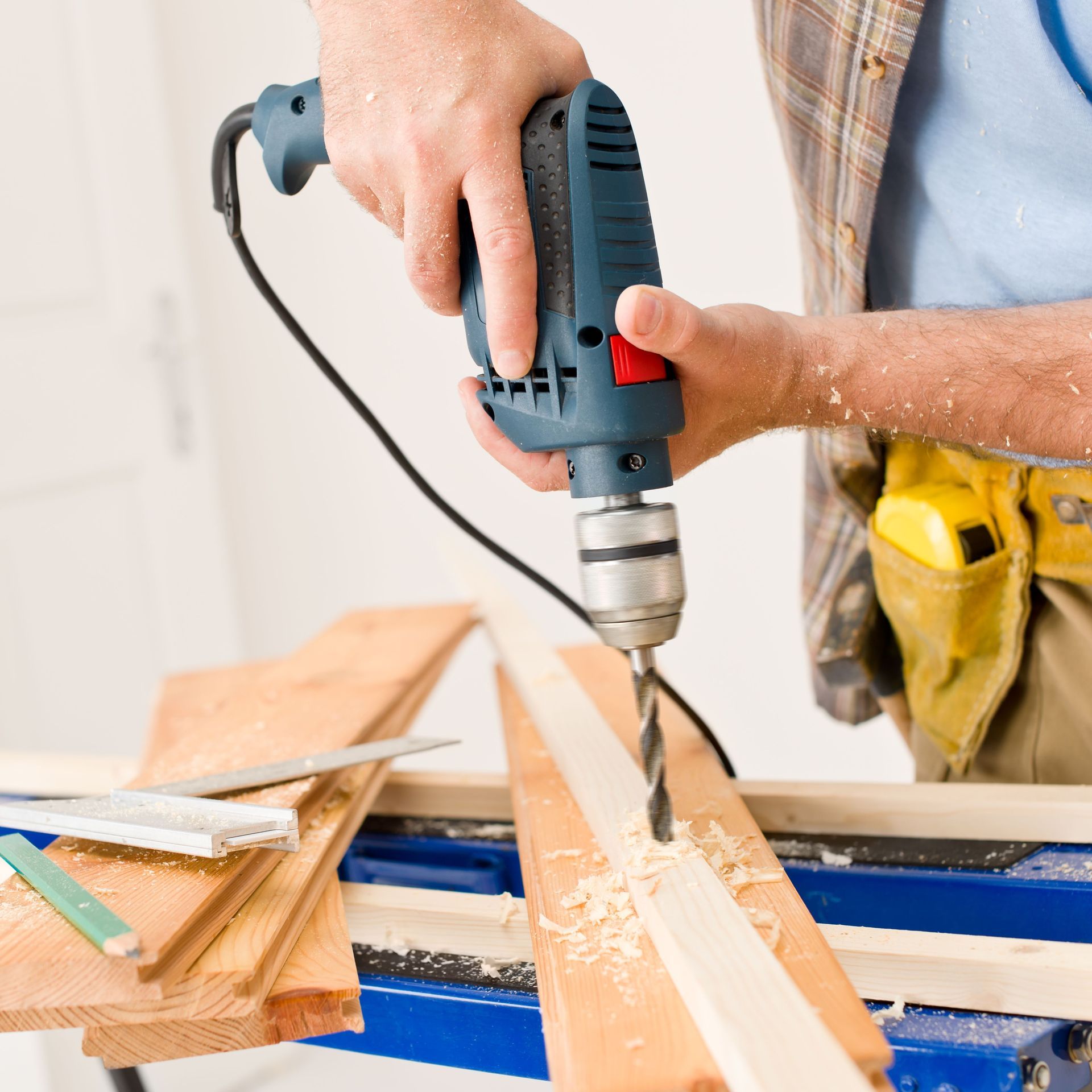 A man is using a drill to drill a hole in a piece of wood