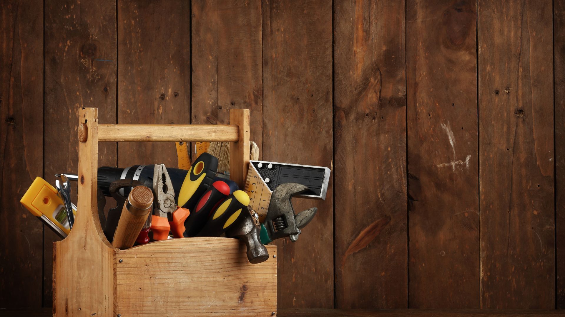 A wooden toolbox filled with tools on a wooden table.