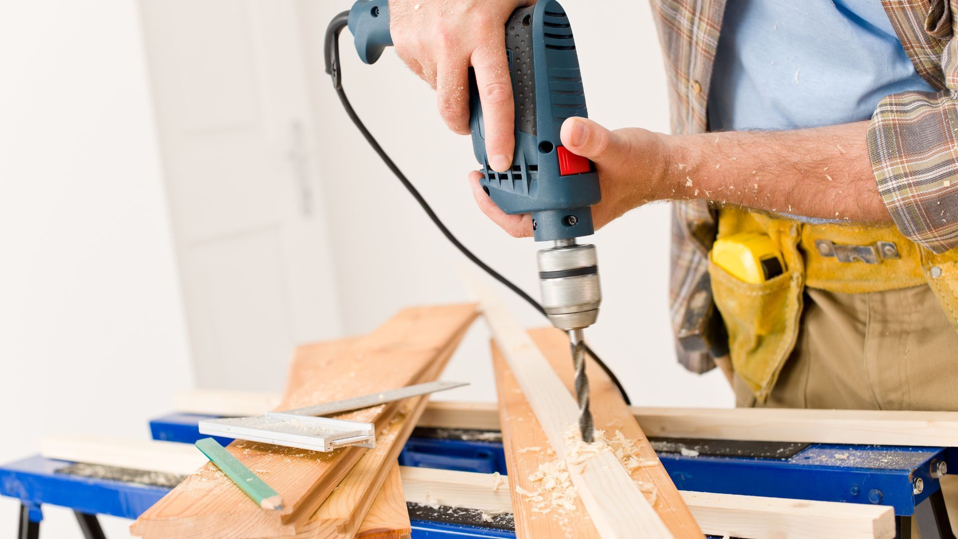 A man is using a drill to drill a hole in a piece of wood.