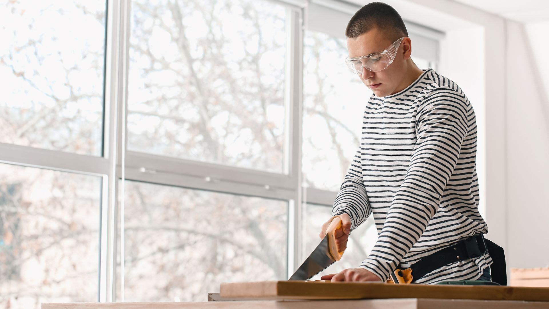 A man is cutting a piece of wood with a saw.
