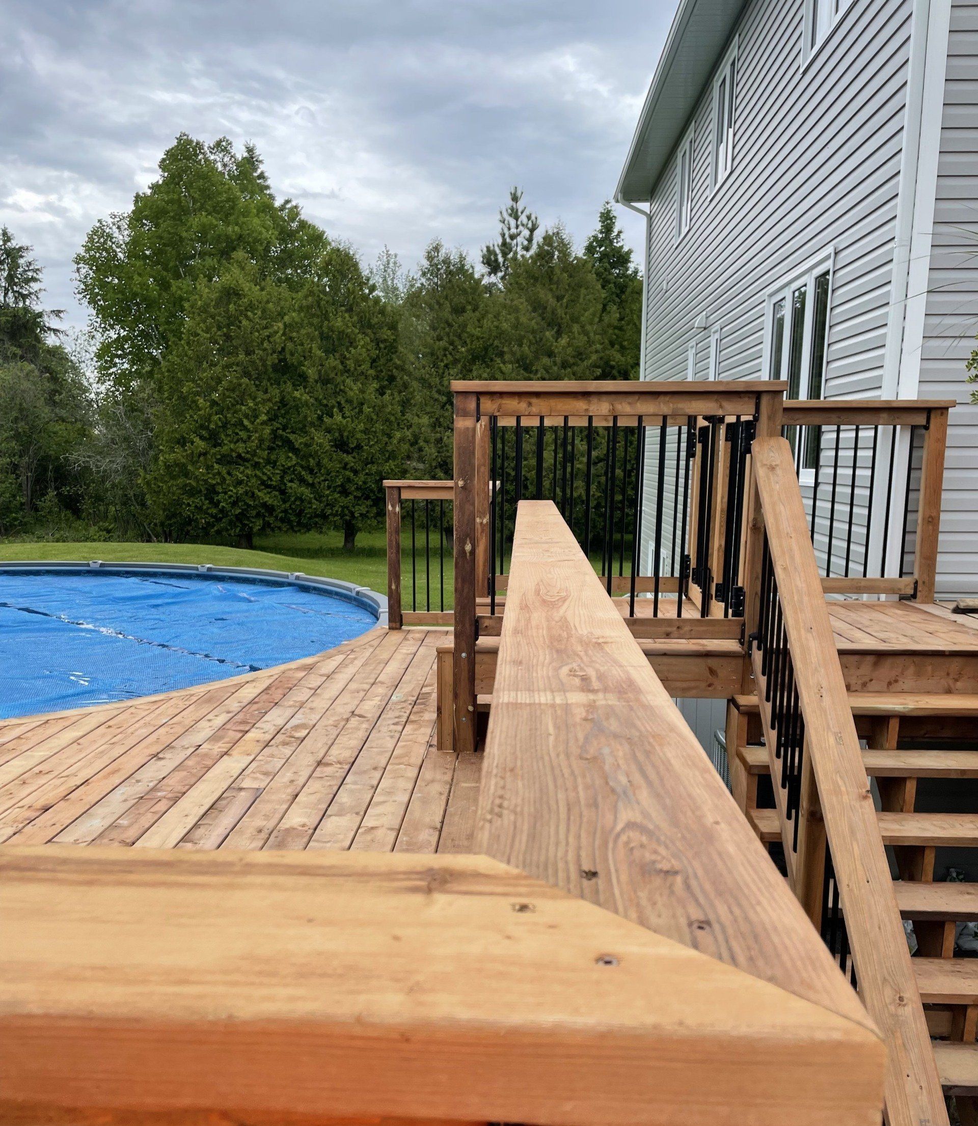 A wooden deck with stairs leading to a swimming pool