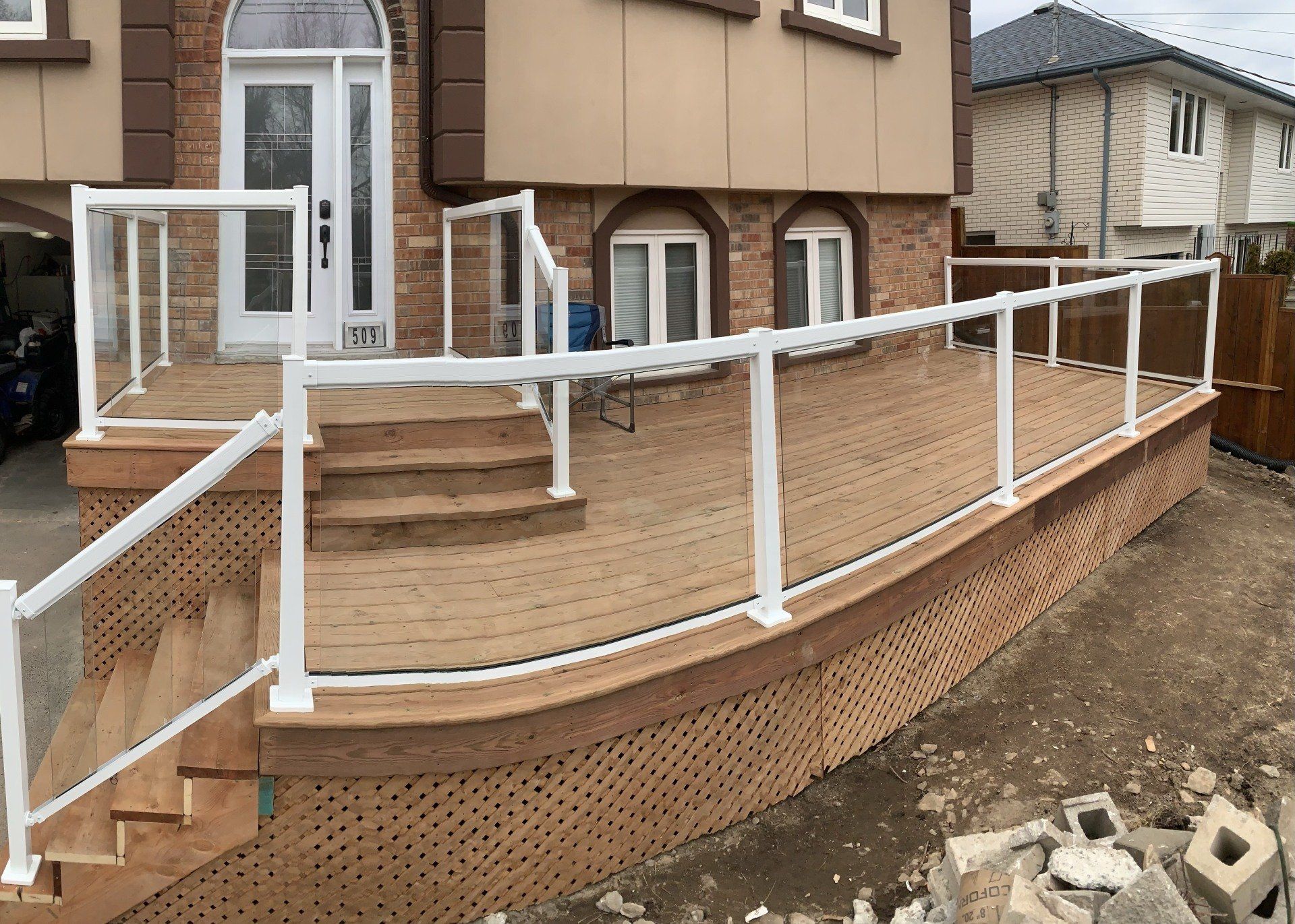 A wooden deck with stairs and a white railing in front of a house.