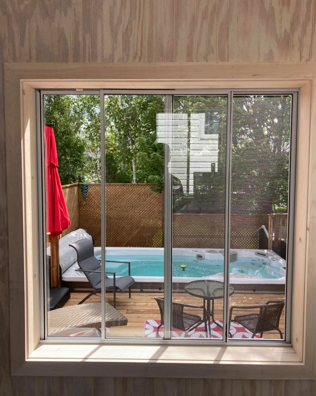 A view of a hot tub through a window with sliding glass doors.