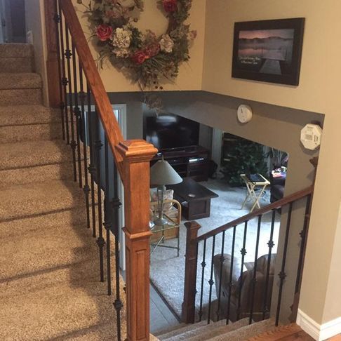 Stairs leading up to a living room with a wreath on the wall