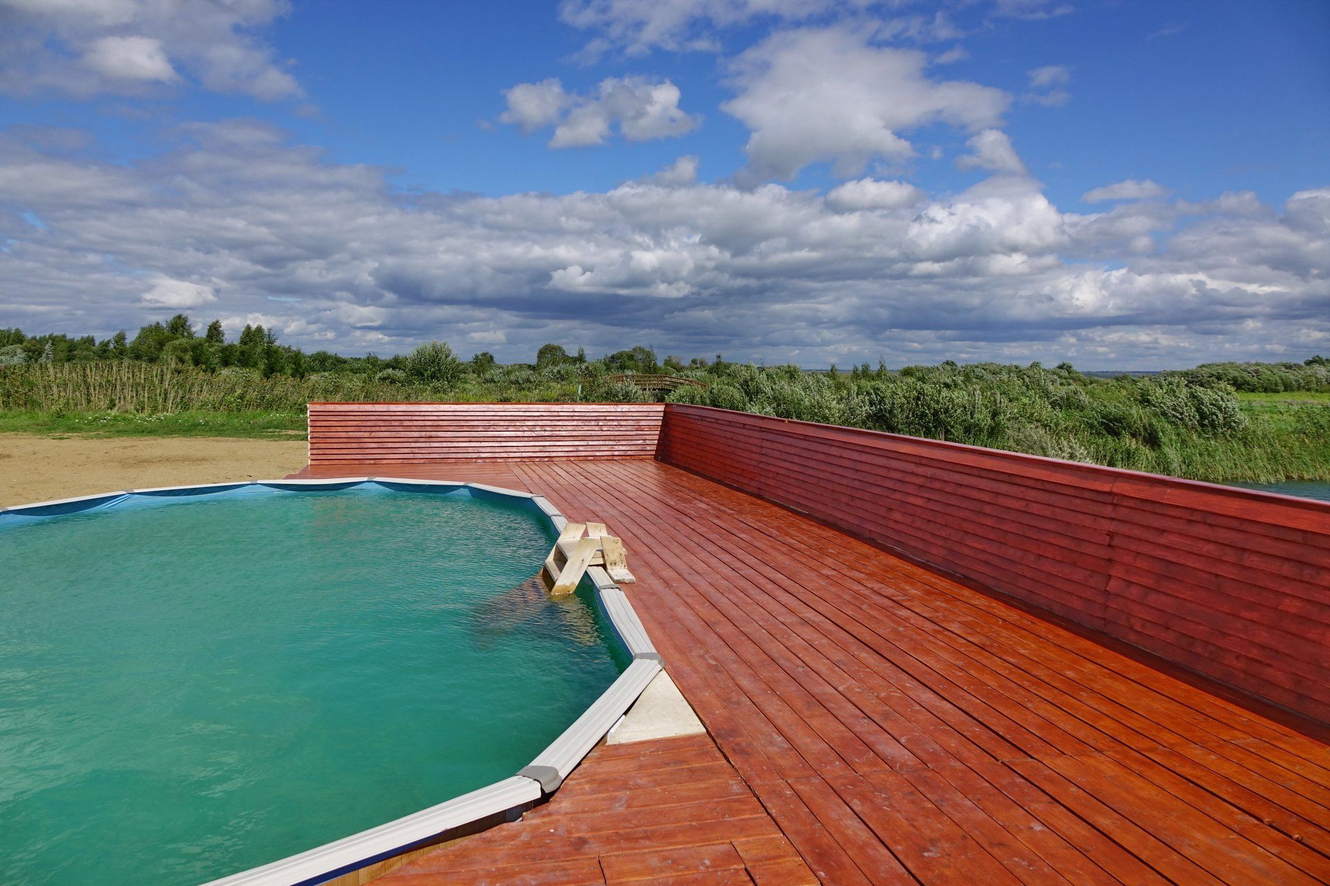 A person is swimming in a pool on a wooden deck.