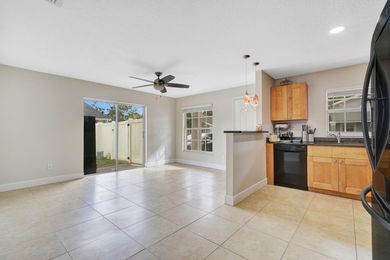 A kitchen and living room in a house with a ceiling fan.