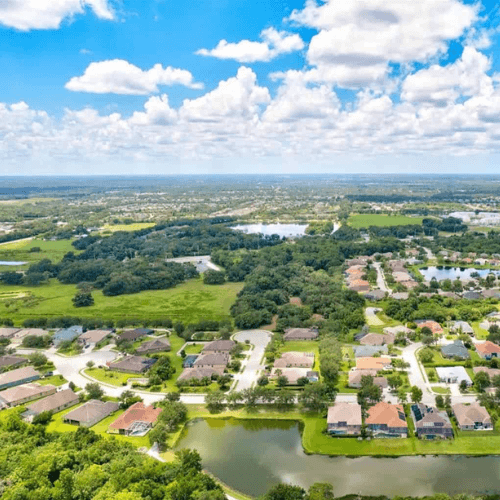 An aerial view of a residential area surrounded by trees and a lake.