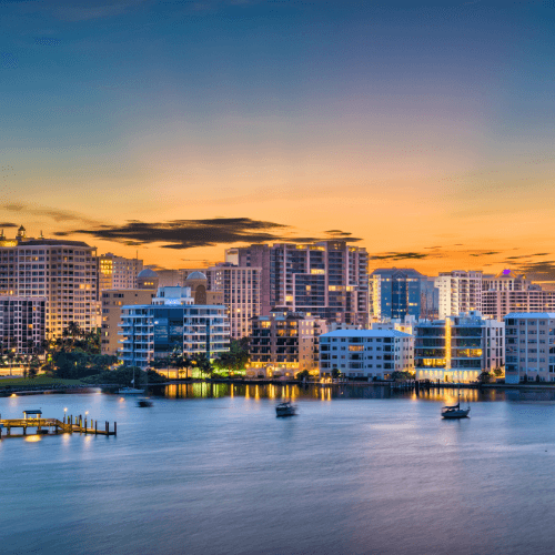 A city skyline with boats in the water at sunset.