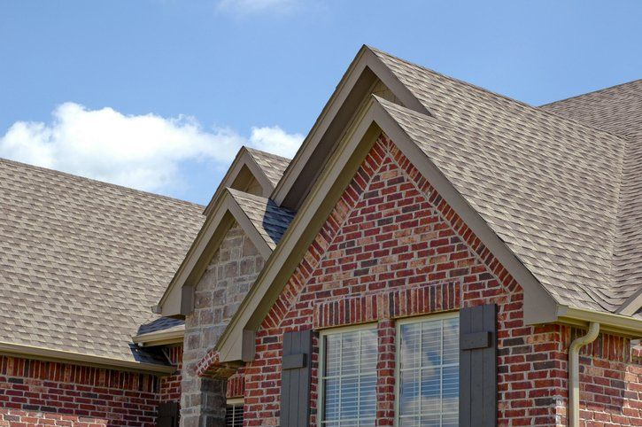 A brick house with a brown roof and black shutters