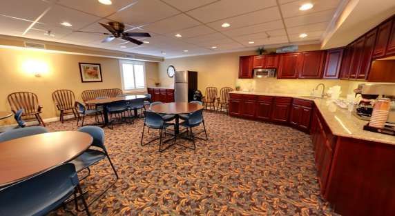 A large room with tables and chairs and a kitchen.