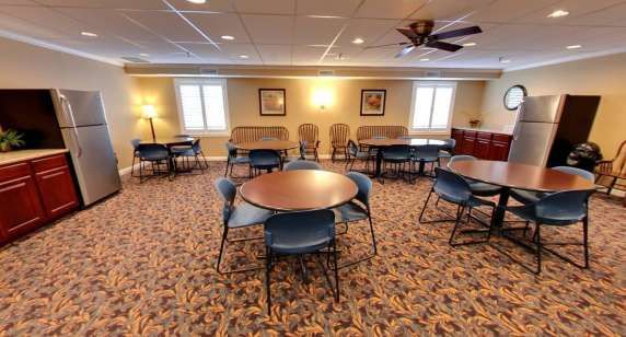 A room with tables and chairs and a ceiling fan