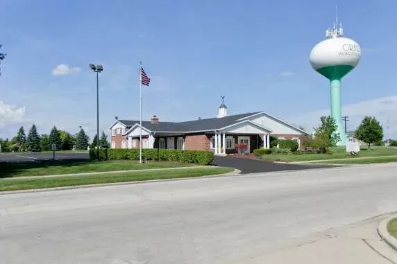 A water tower is in front of a building in a residential area.