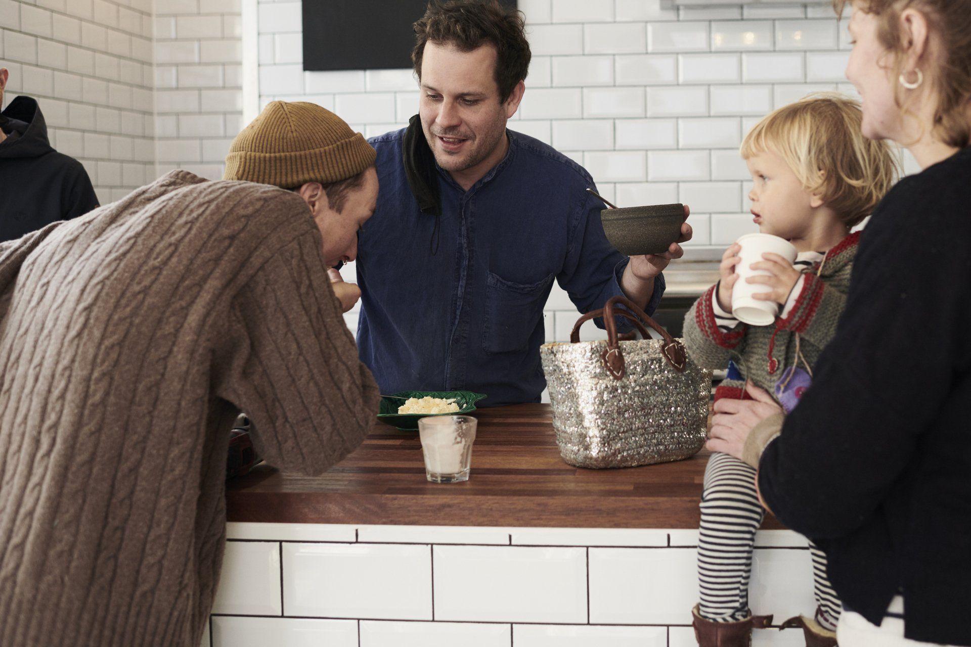 A group of people are standing around a counter in a kitchen.