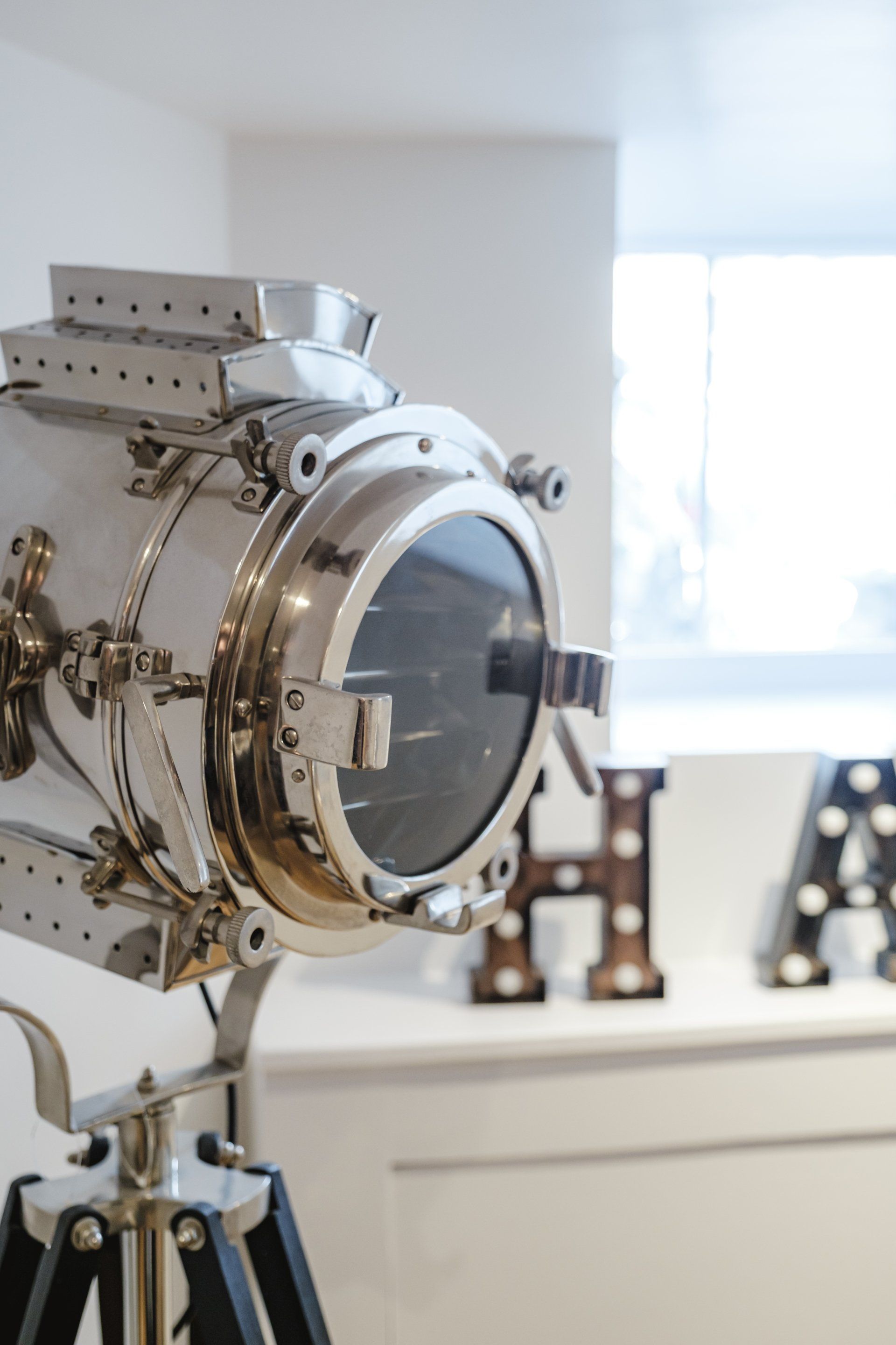 A spotlight is sitting on a tripod in front of a window.