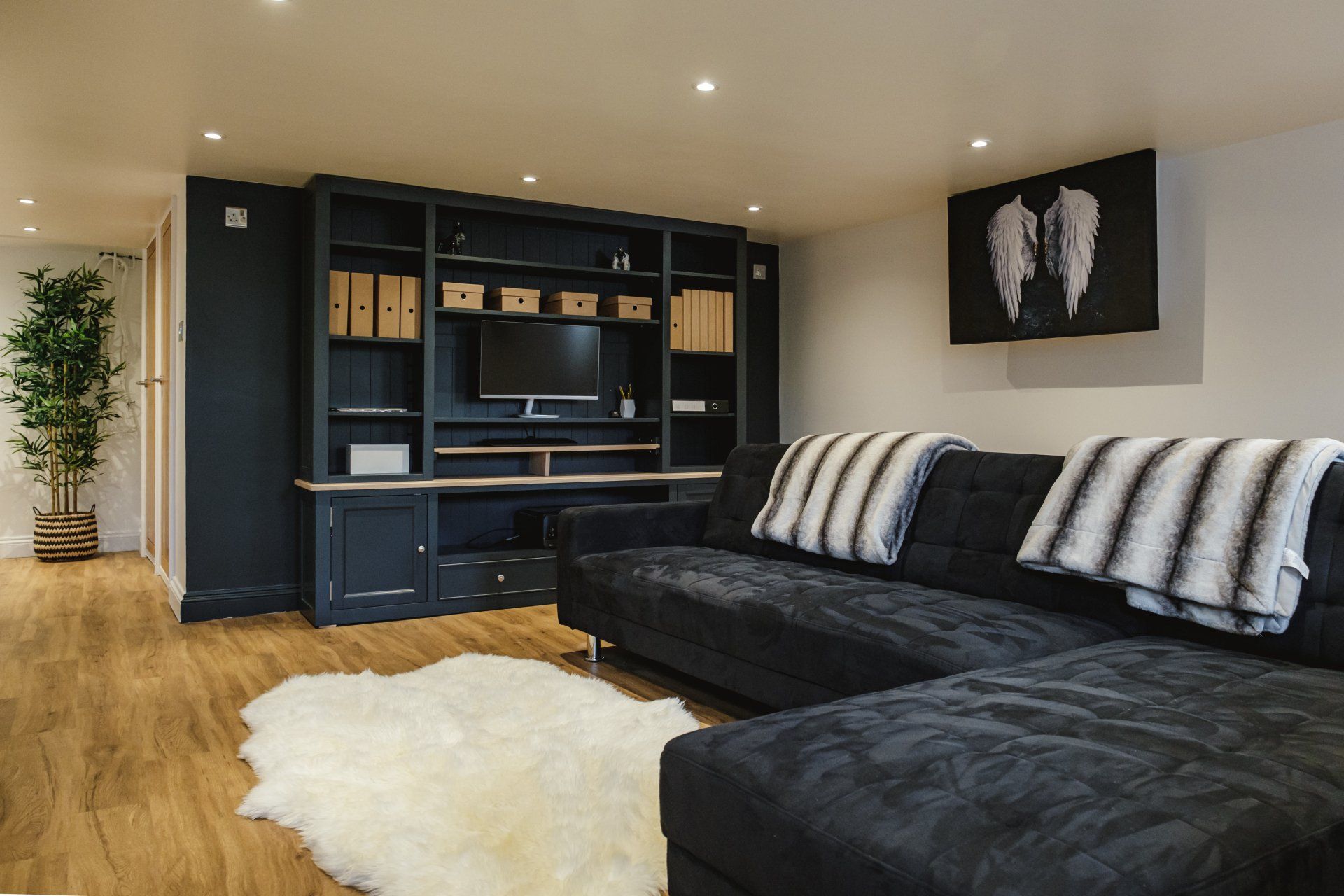 A living room with a black couch and a white rug.