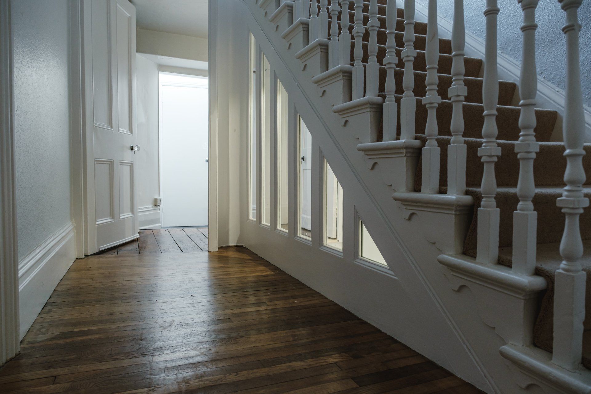A hallway with wooden floors and stairs in a house.