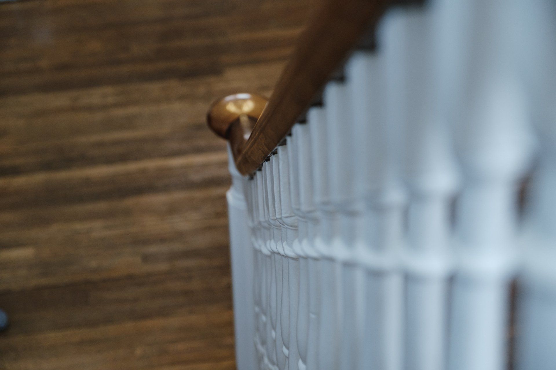 A close up of a white railing on a wooden staircase.