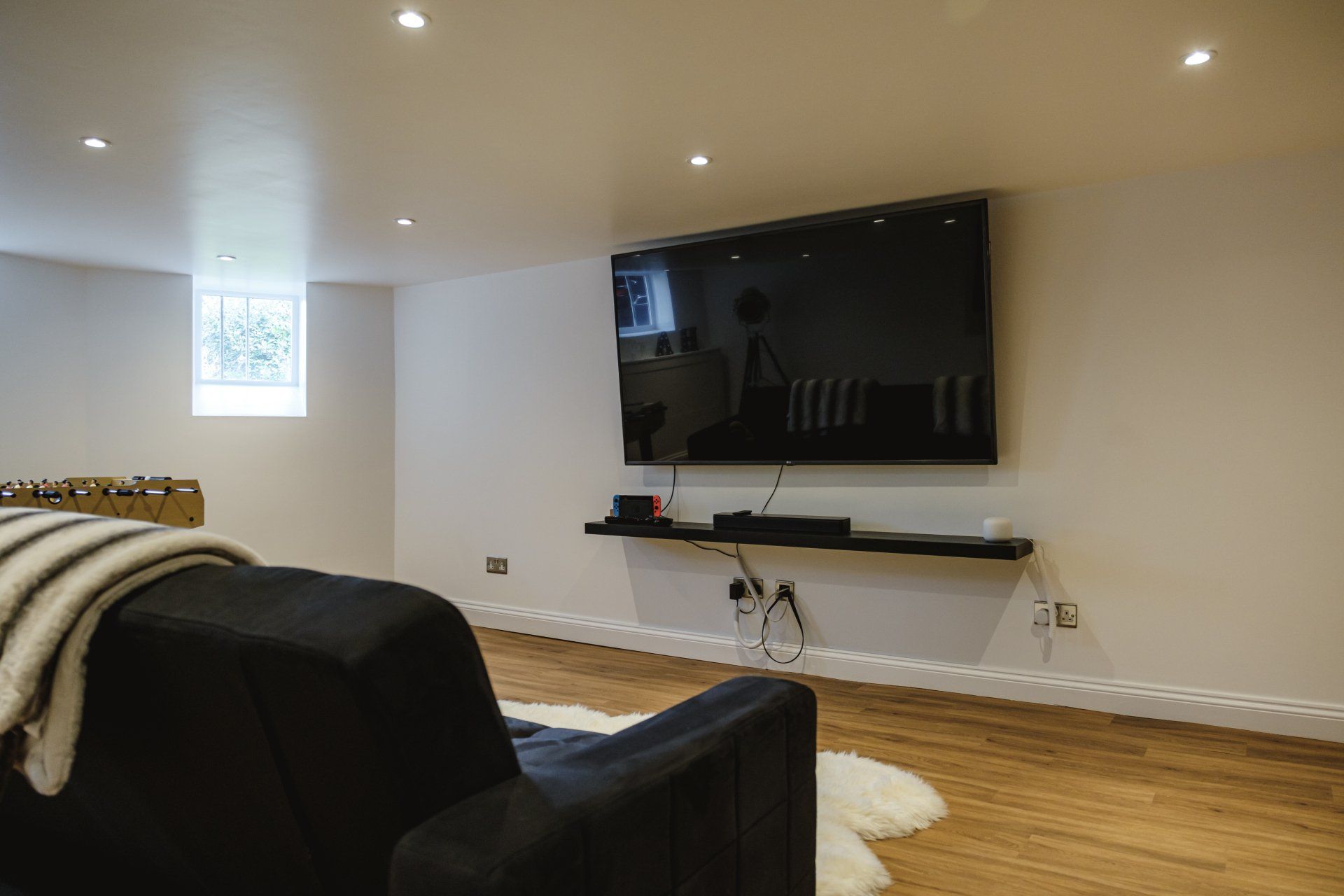 A living room with a couch and a flat screen tv on the wall.