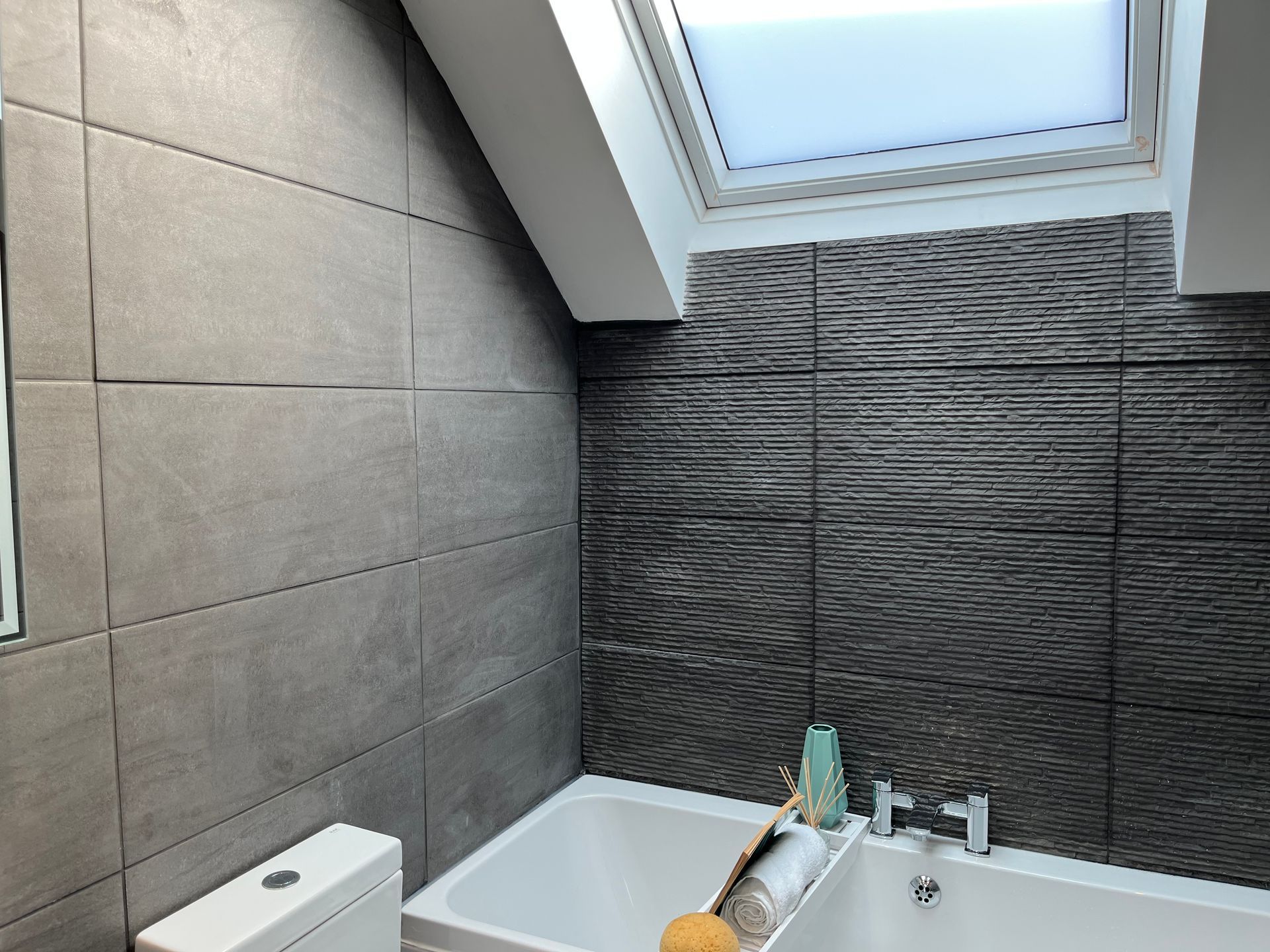 A bathroom with a bathtub a toilet and a skylight