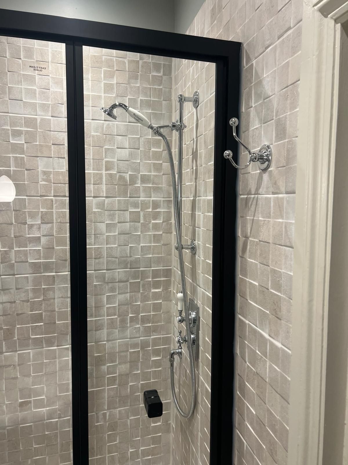 A shower with a sliding glass door and a shower head.