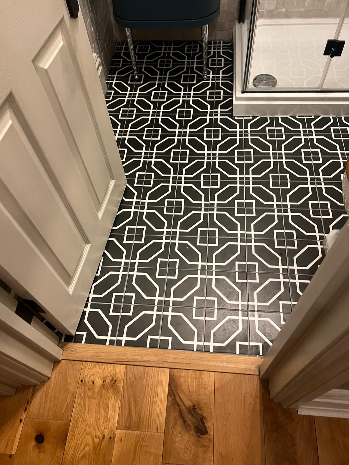 A bathroom with a black and white tile floor and a wooden floor.