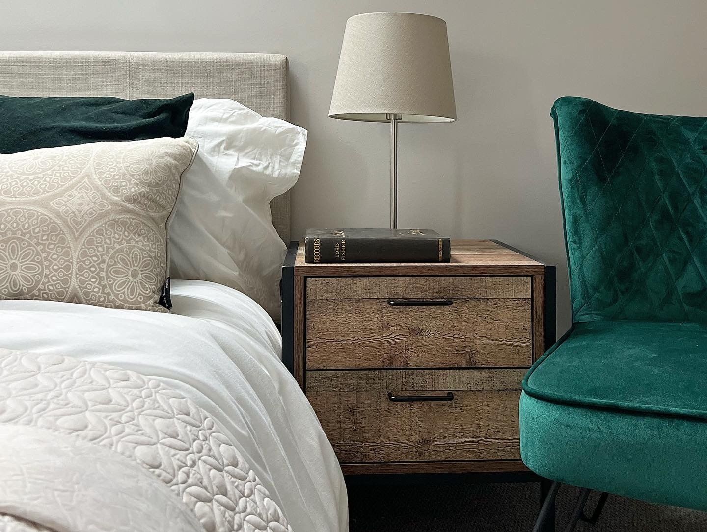 A bedroom with a bed , chair , nightstand and lamp