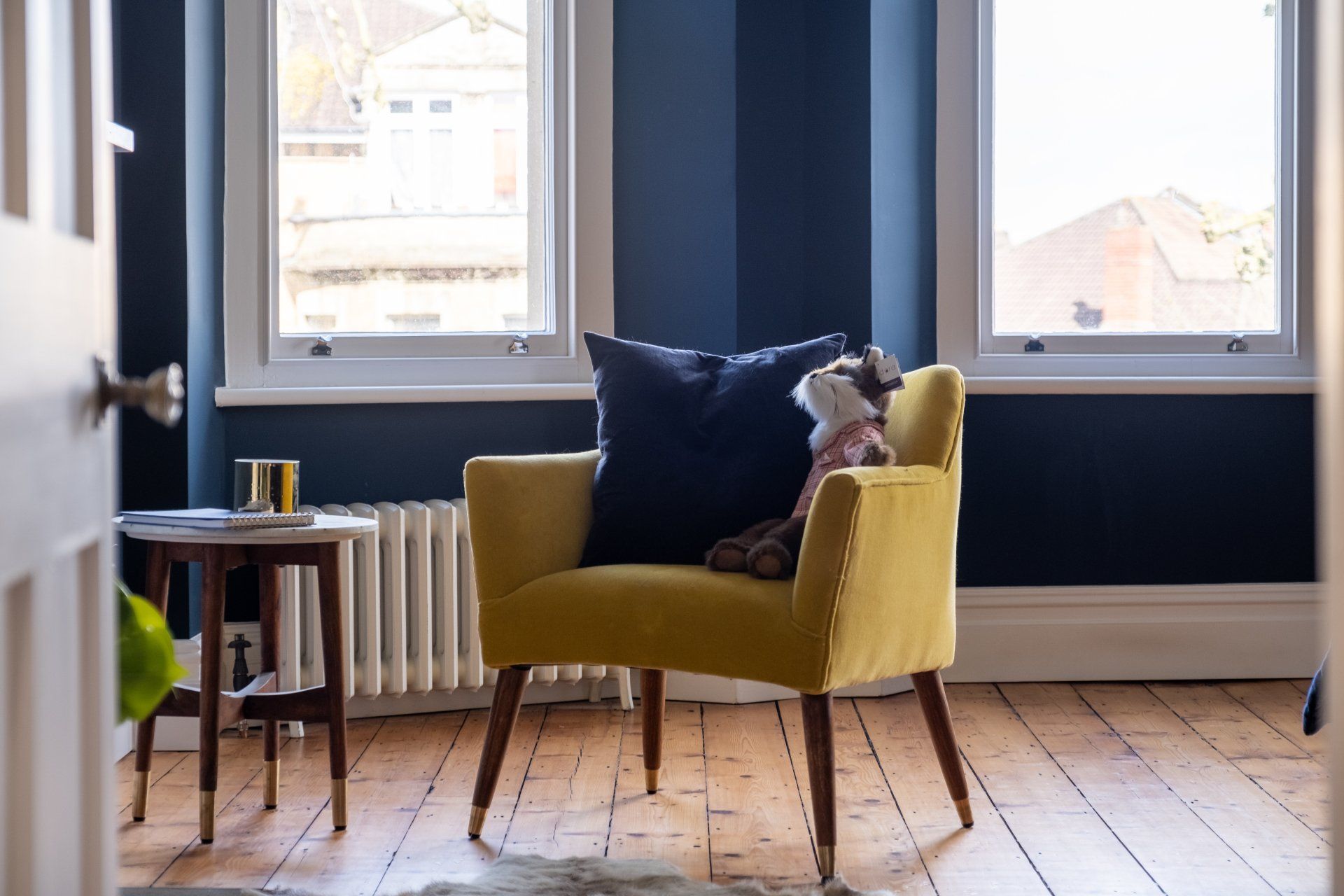A yellow chair with a black pillow on it is sitting in a living room.