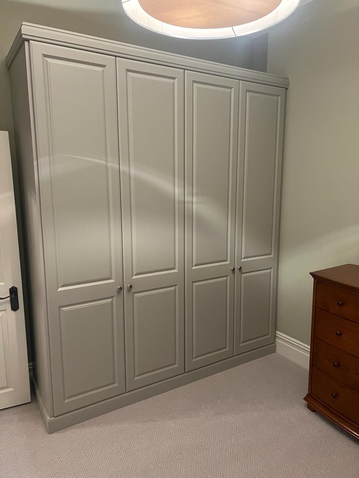 A large grey wardrobe is sitting in a bedroom next to a dresser.