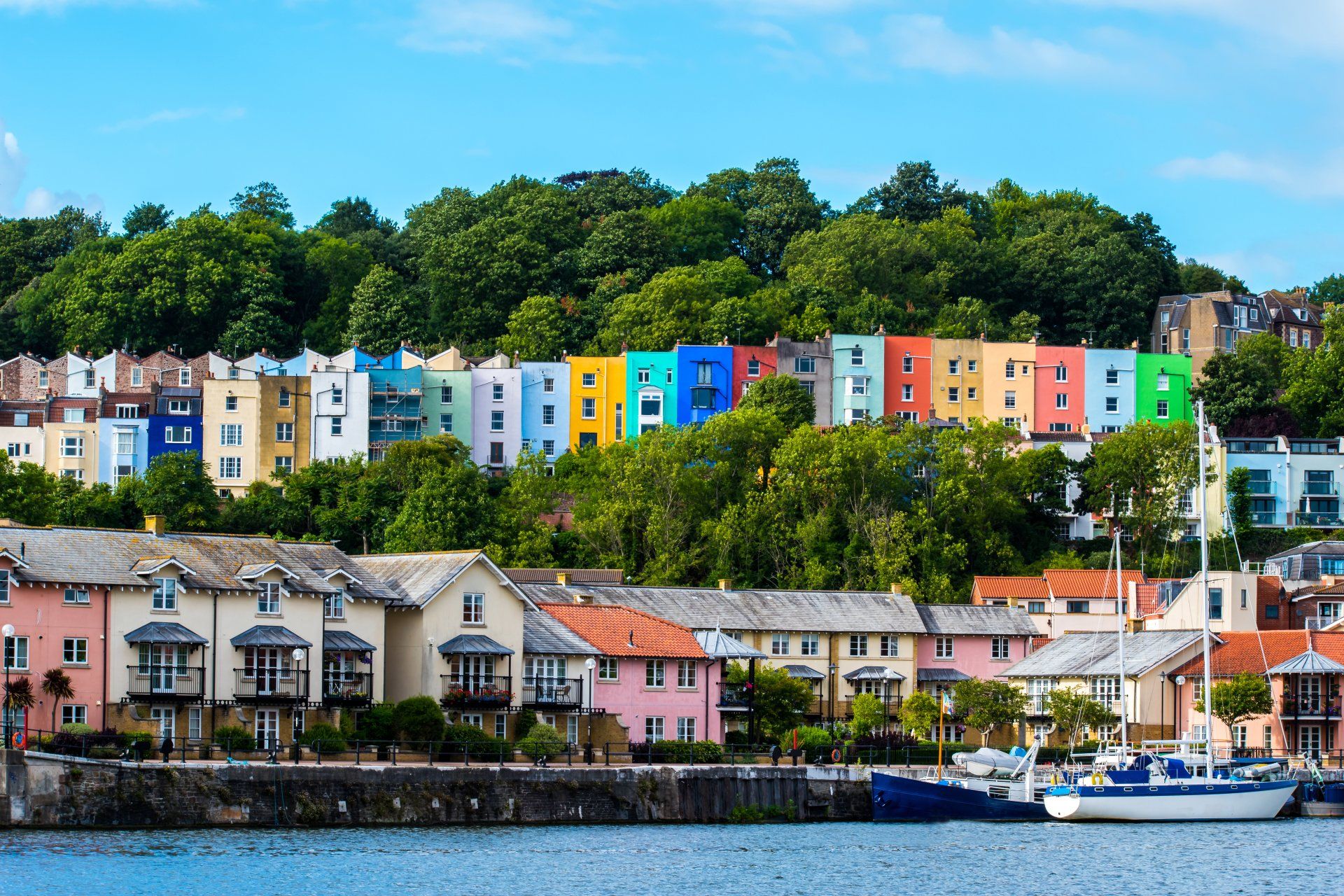 A row of colorful houses on a hill overlooking a body of water.