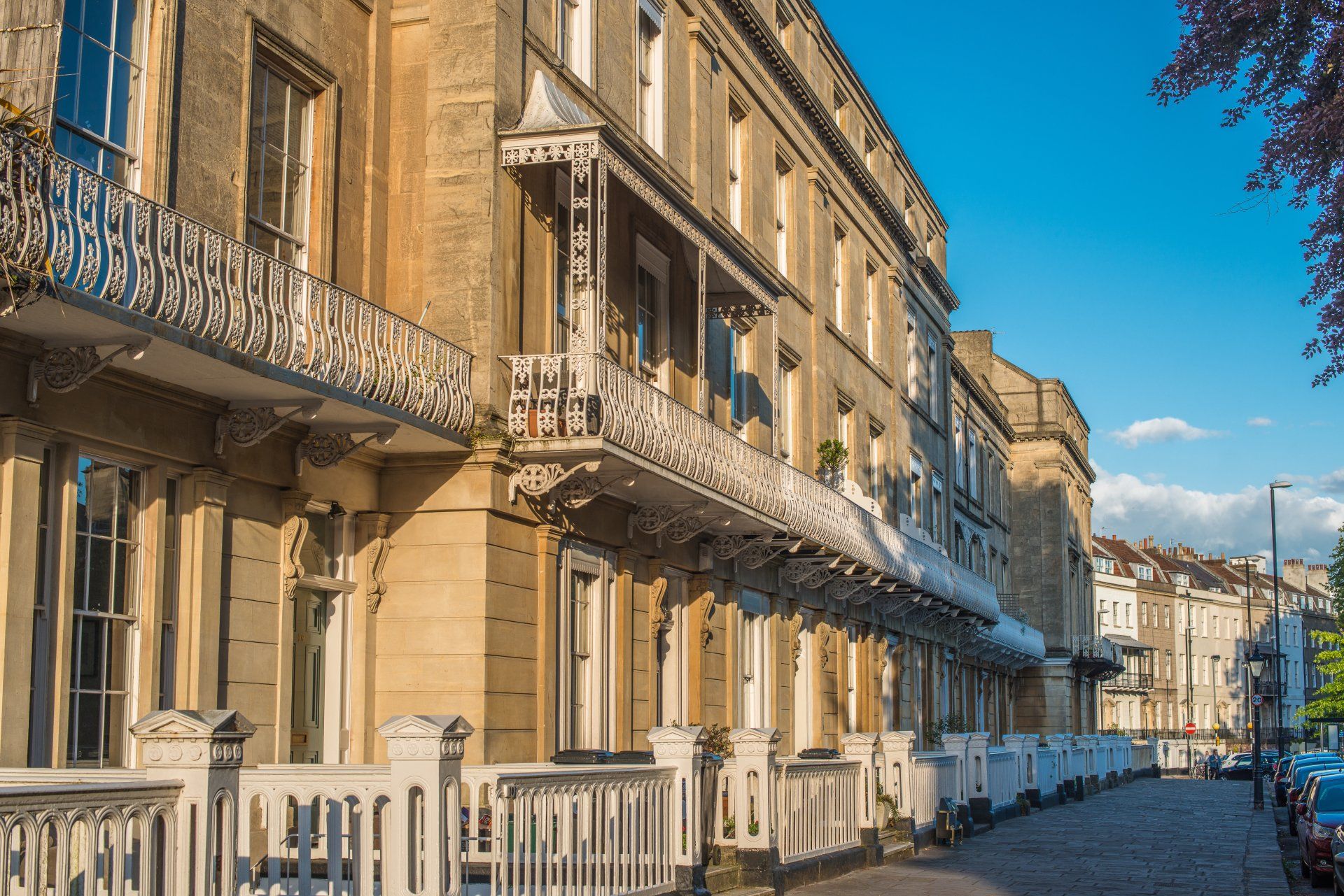 A row of buildings with balconies on the side of a street.