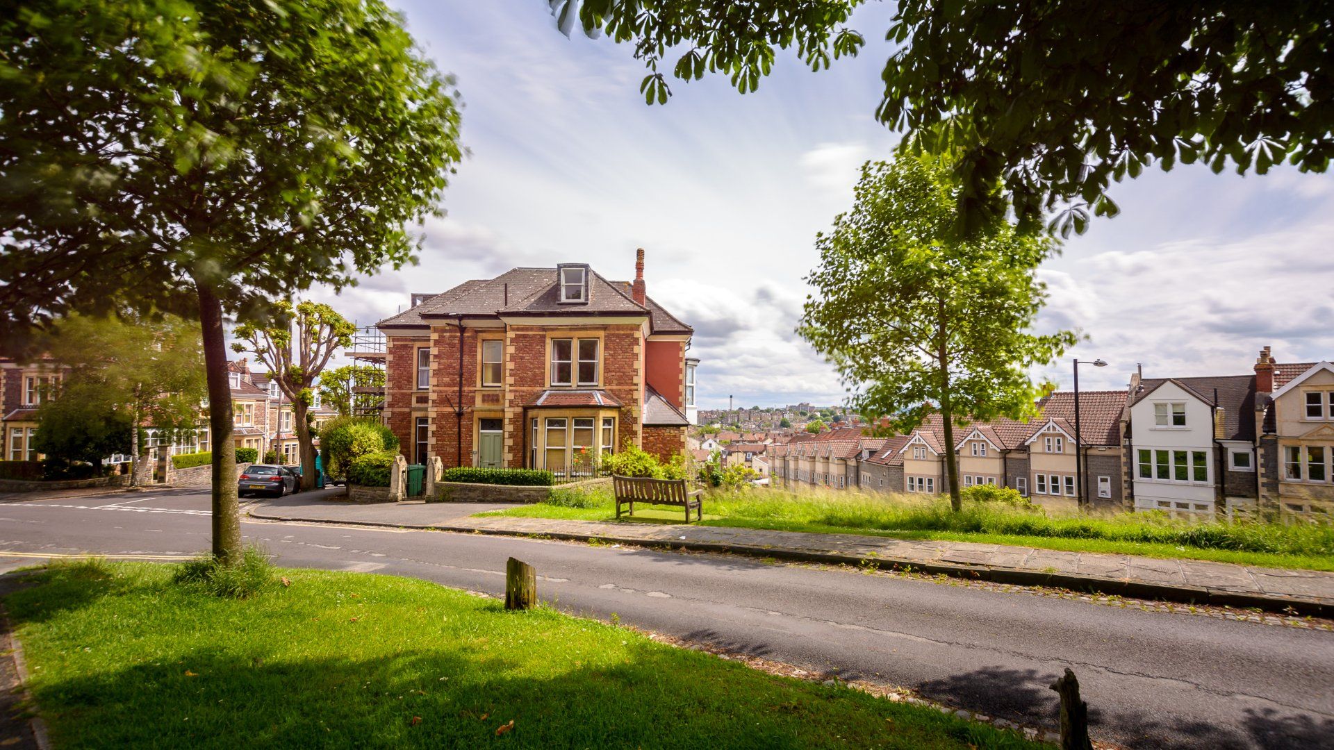 A brick house is sitting on the corner of a street next to a tree.