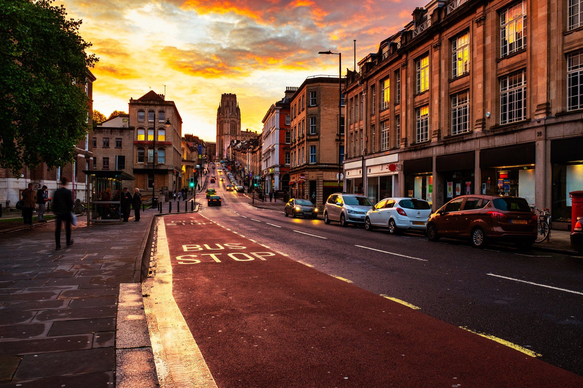 A city street with cars parked on the side of it at sunset.