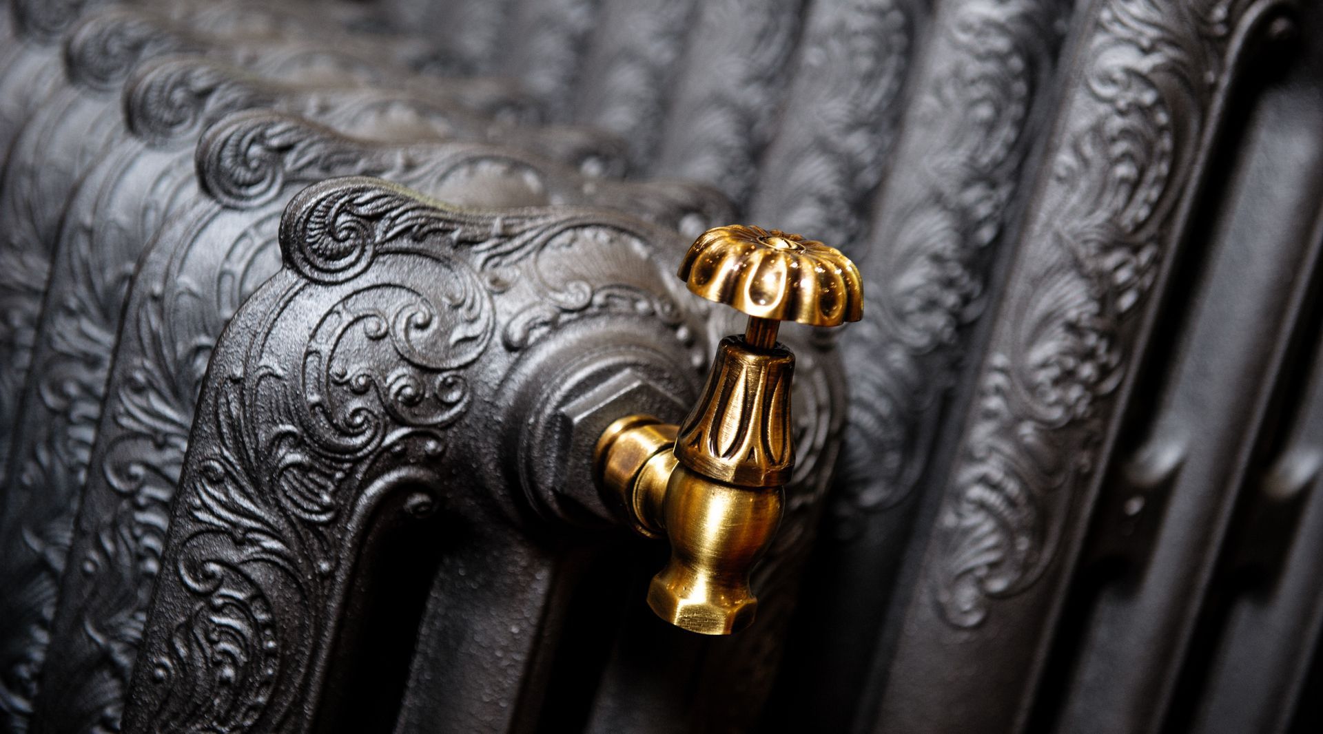 A close up of a black radiator with a gold valve.