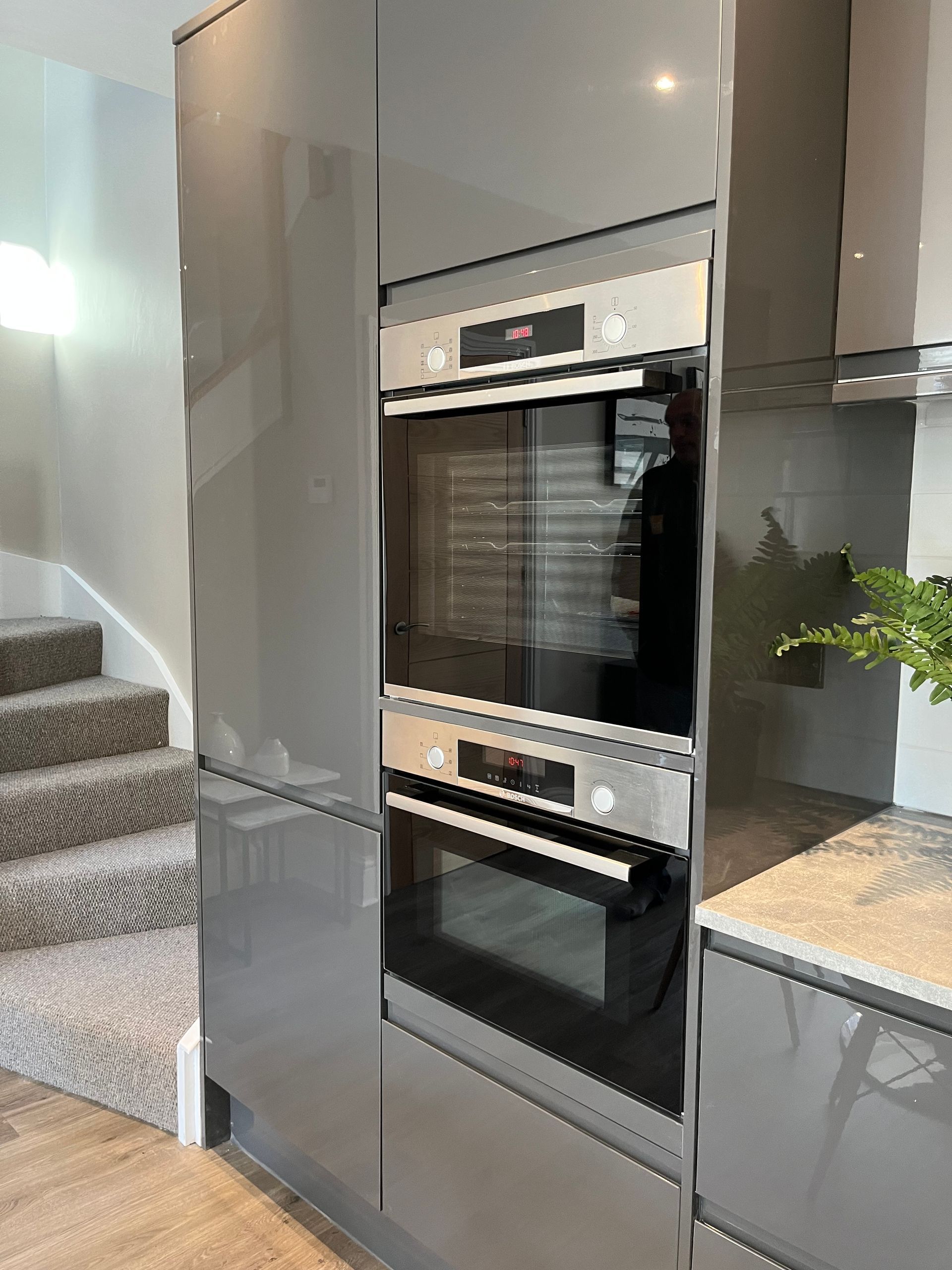 A kitchen with gray cabinets and a stainless steel oven.
