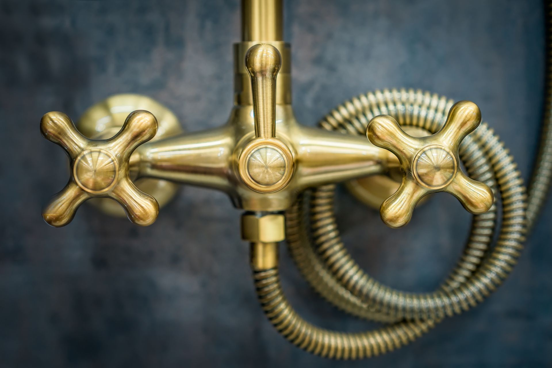 A close up of a brass shower head with a hose attached to it.