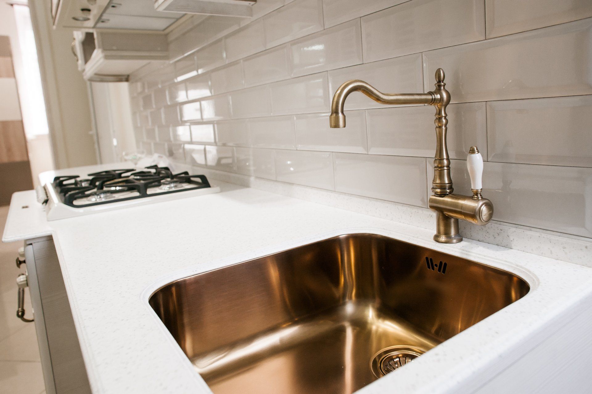 A kitchen with a copper sink and a brass faucet.