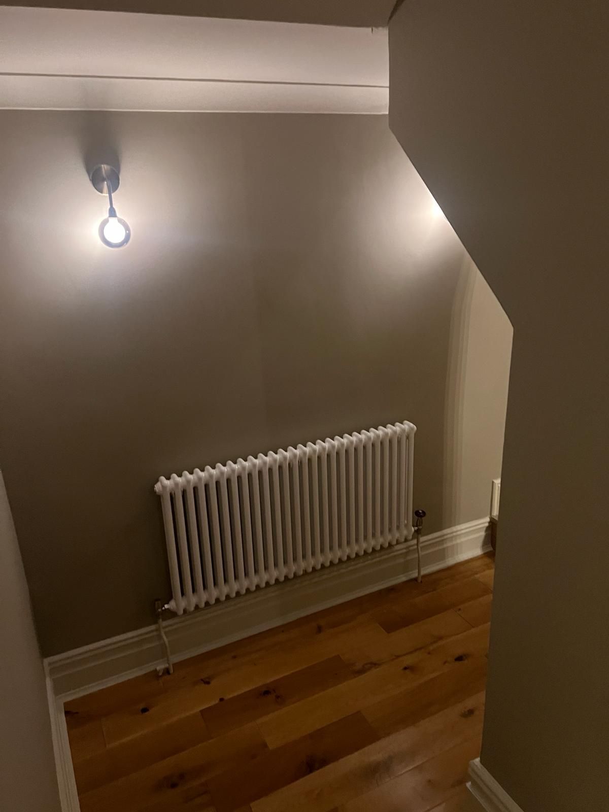 A room with a radiator and a light on the wall.