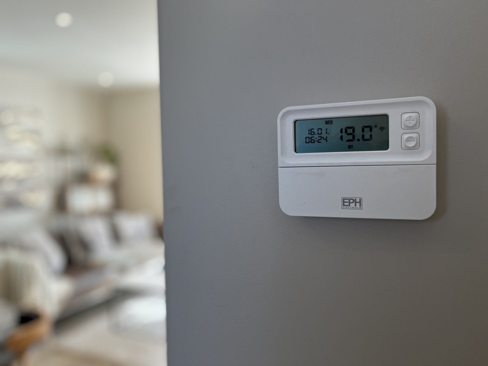 A thermostat is hanging on a wall in a living room.