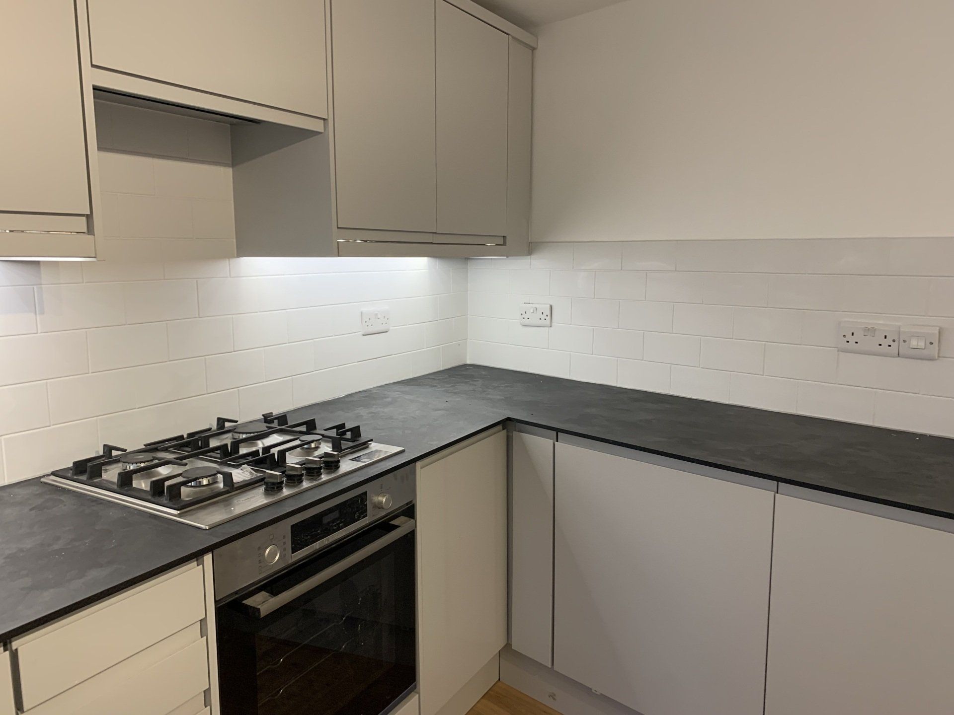 A kitchen with white cabinets and a stove top oven.