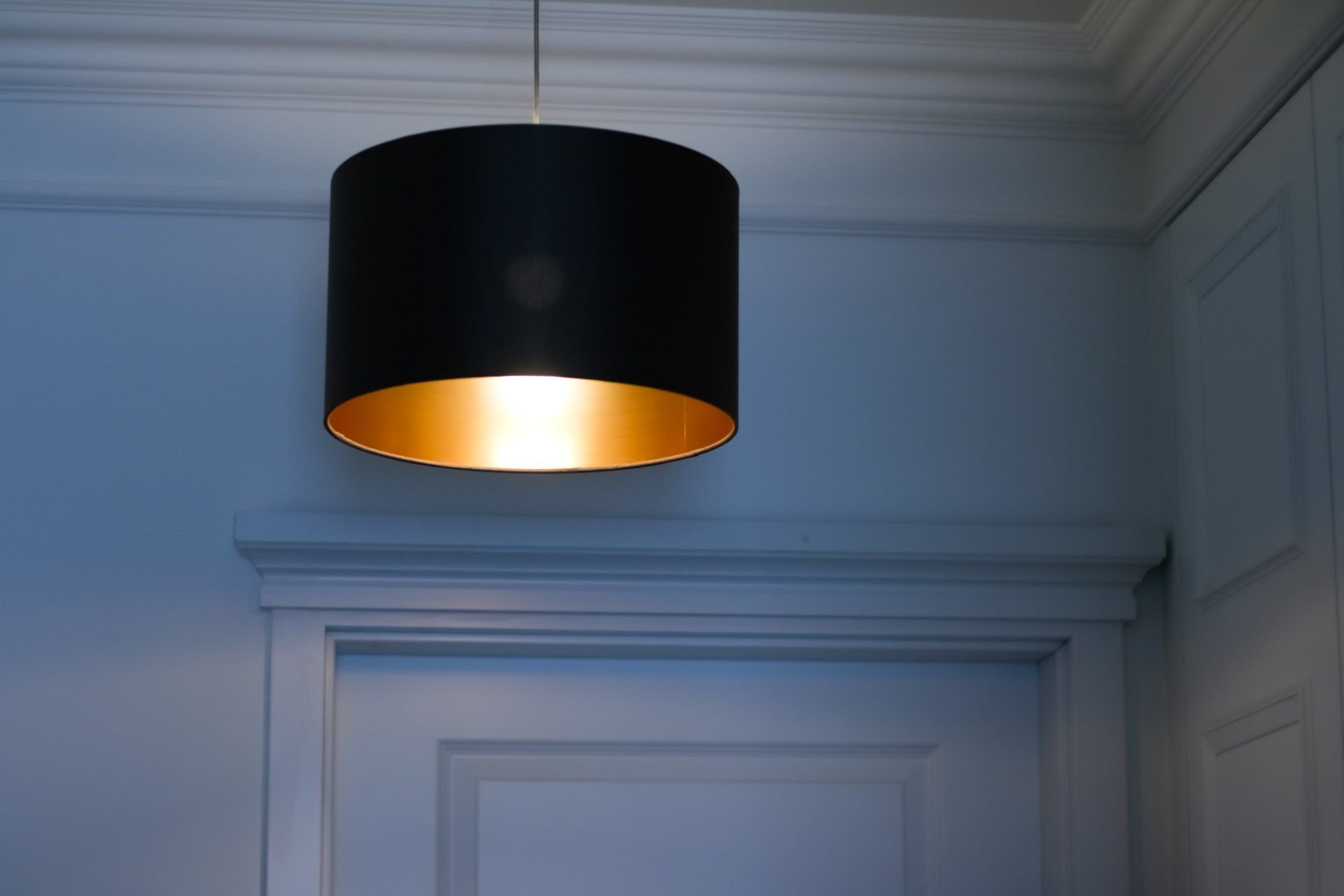 A black lamp with a gold inside is hanging from the ceiling