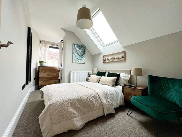 A bedroom with a large bed and a green chair.